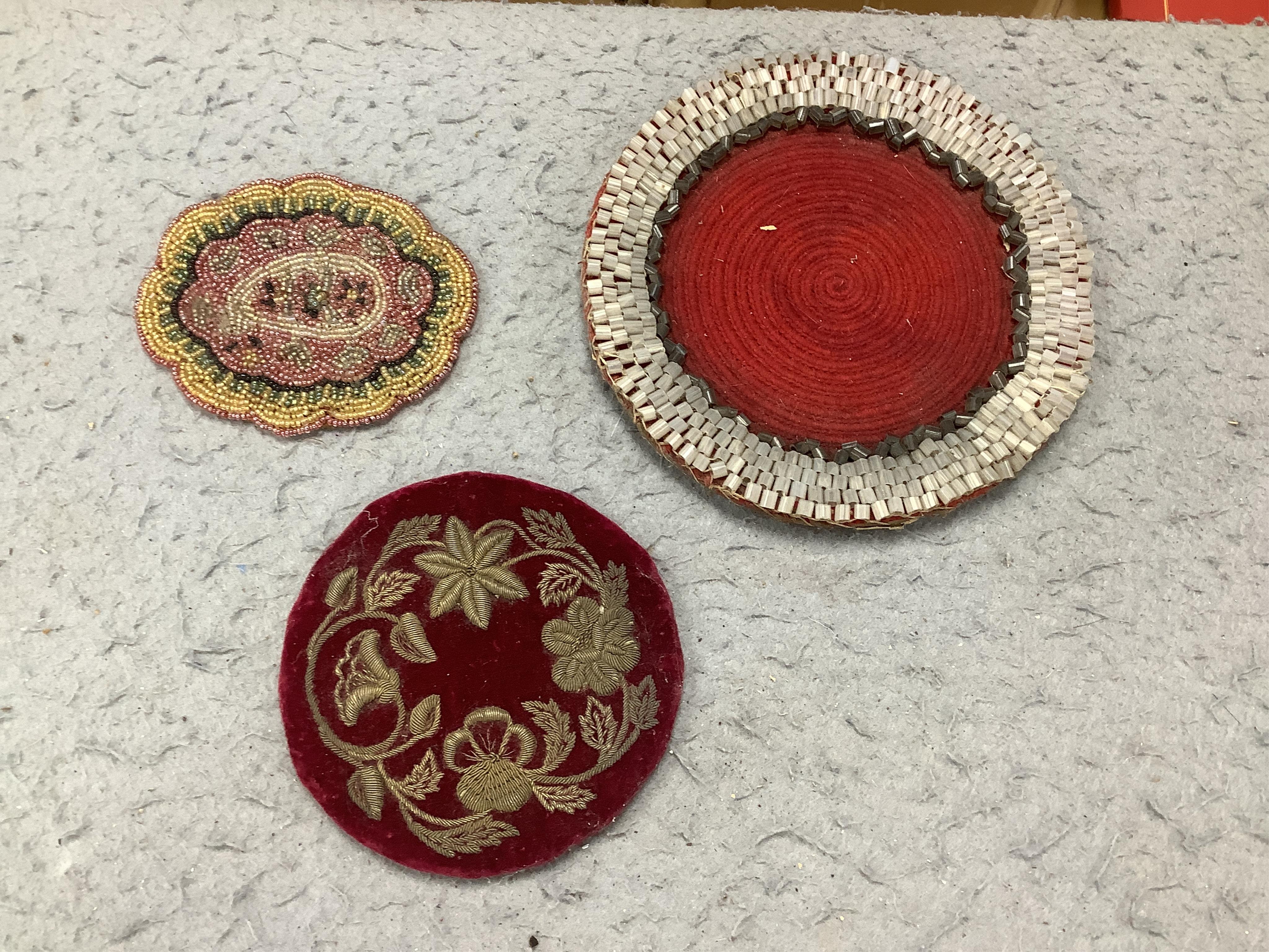 A 19th century framed needlework panel of a dog (possibly a teapot stand), a collection of bead worked mats, a beaded and tasselled tie-back and a large pin cushion, dog needlework 22.5cm wide. Condition - some beads mis